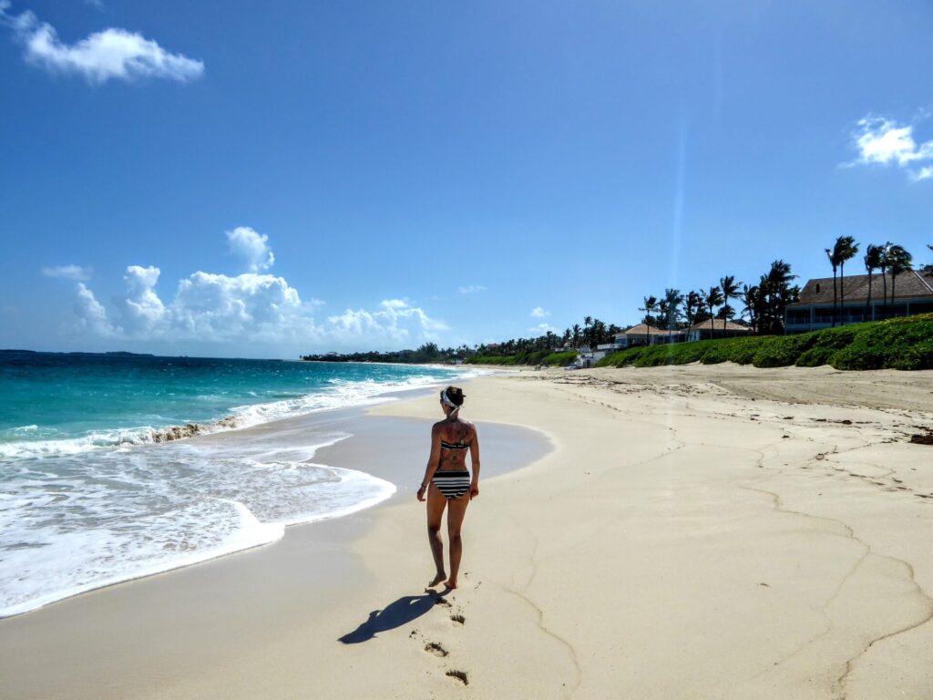 Frau geht am Strand mit türkisem Meer in Nassau auf den Bahamas
