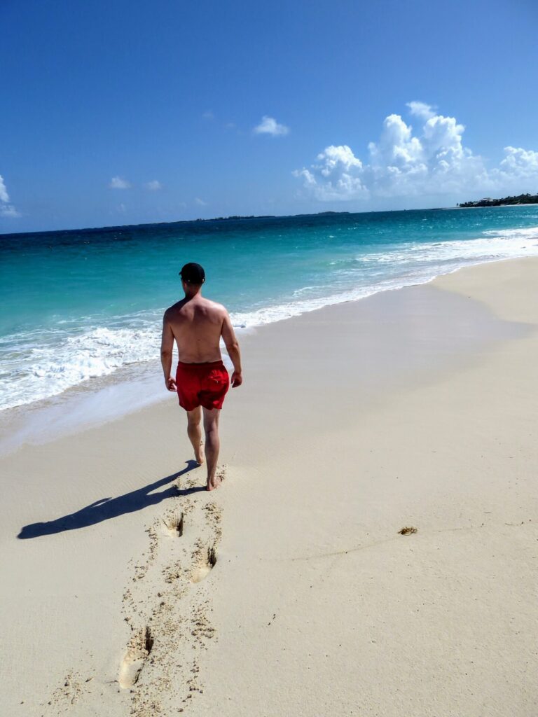 Mann geht am Stand mit türkisem Meer in Nassau auf den Bahamas