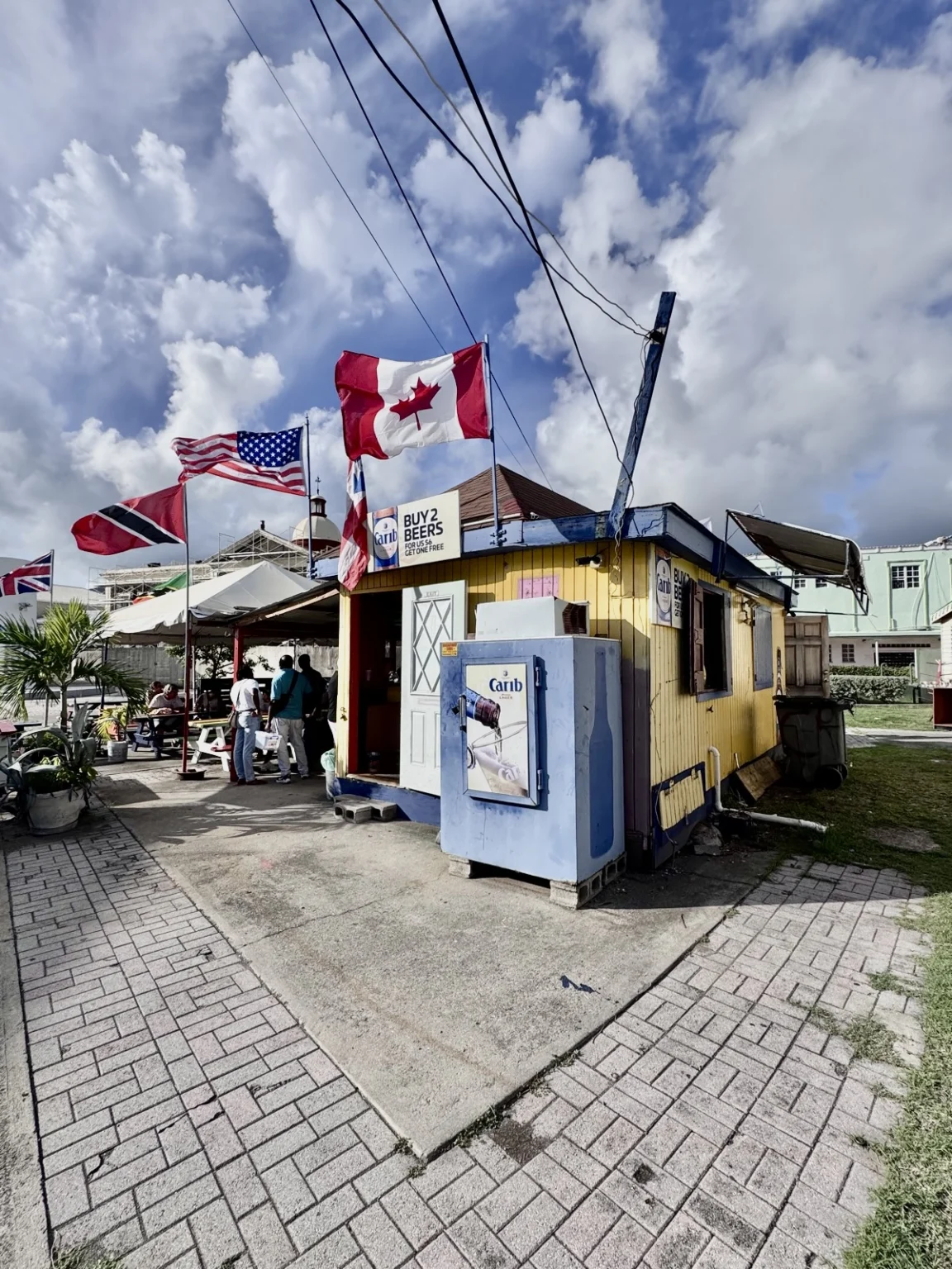 Lokaler Rum Shop in St. Kitts mit kanadischen und amerikanischen Flaggen, gelber karibischer Laden