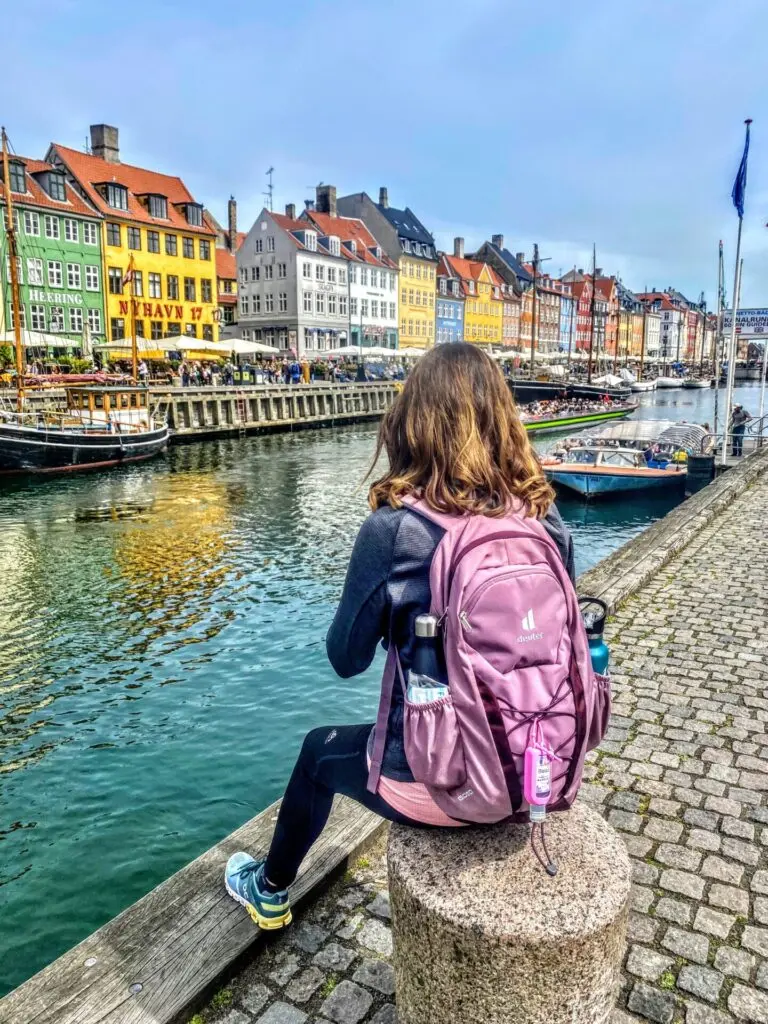 Bunte Häuser am Nyhavn mit sitzender Frau in Kopenhagen