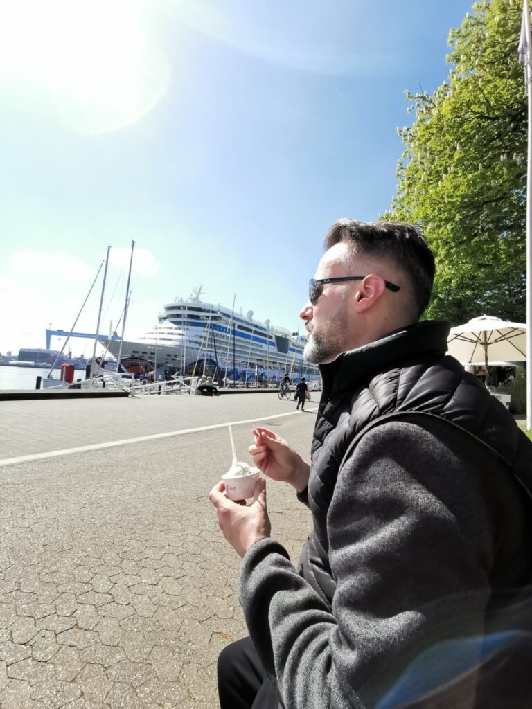 Mann mit Eis und Kreuzfahrtschiff in Kiel