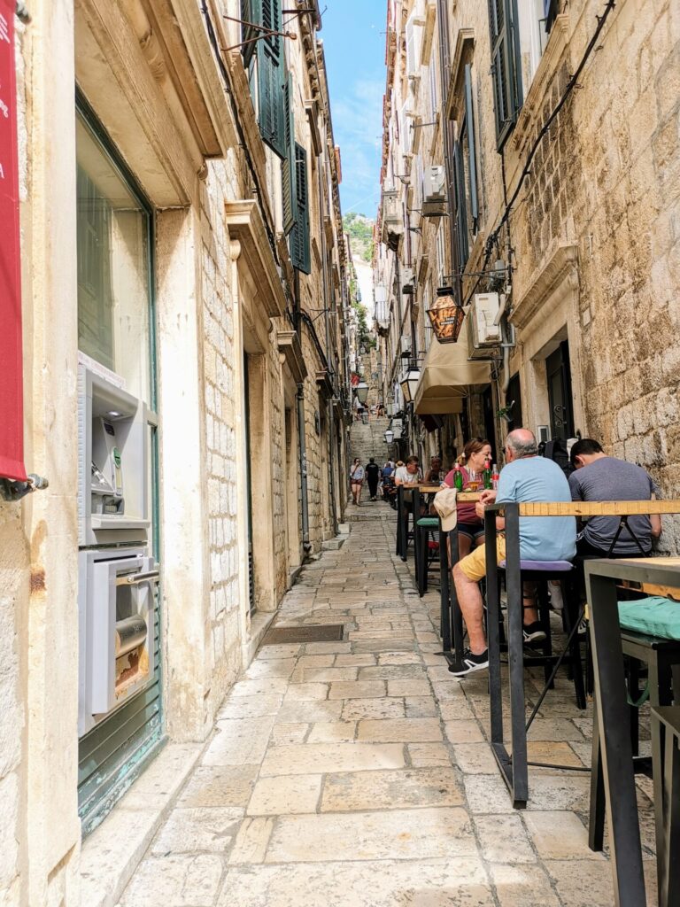 Schmale Gasse mit Tischen und Menschen in Dubrovnik