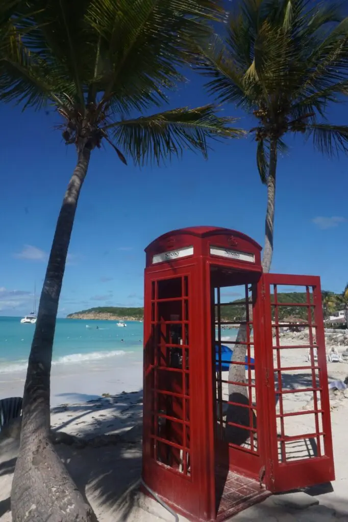Rote Telefon-Zelle am  Strand mit türkisem Meer auf Antigua St. Johns
