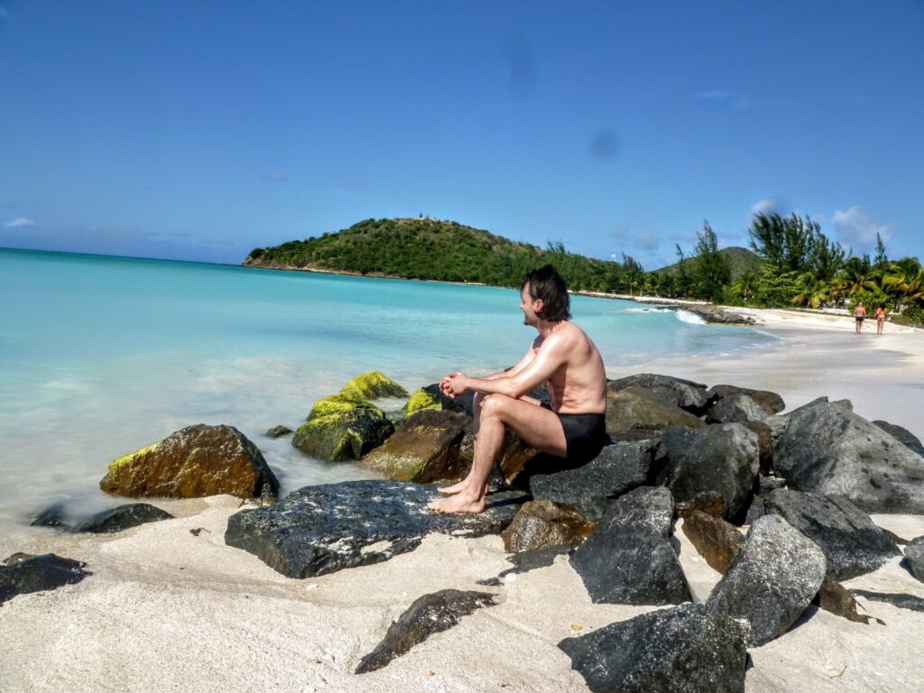 Mann am Strand mit türkisem Meer auf Antigua St. Johns