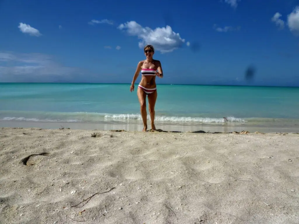 Frau im Bikini am Strand mit türkisem Meer auf Antigua St. Johns