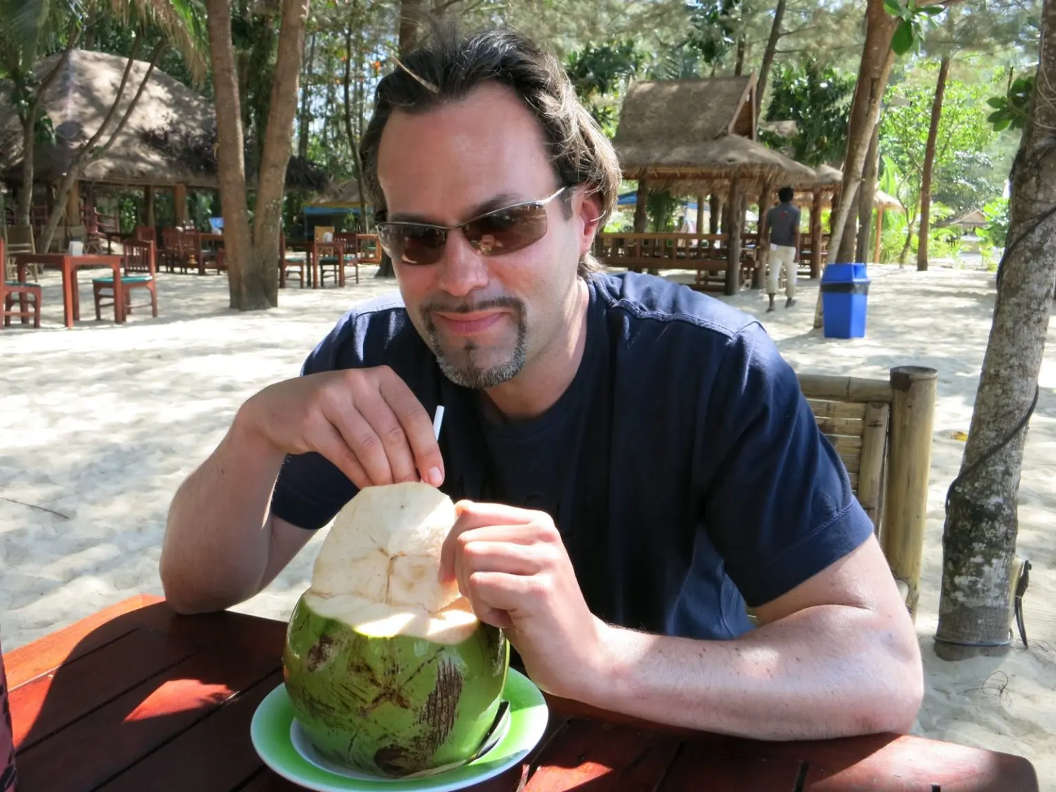 Mann am Strand mit Kokosnuss in Thailand