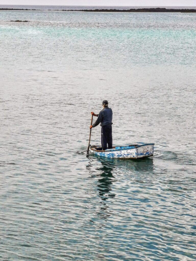 Mann rundert in einem Boot am Hafen von Arrecife