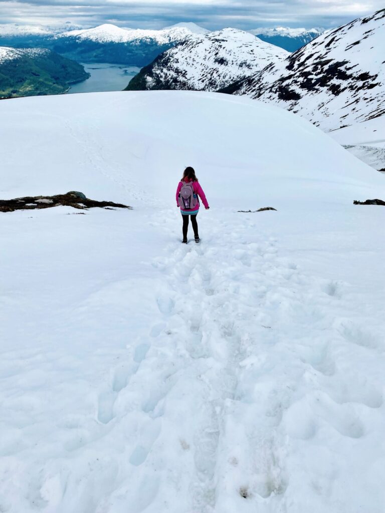 Ausblick vom Hoven auf Olden und die schneebedeckte Berglandschaft mit Fjord mit Frau