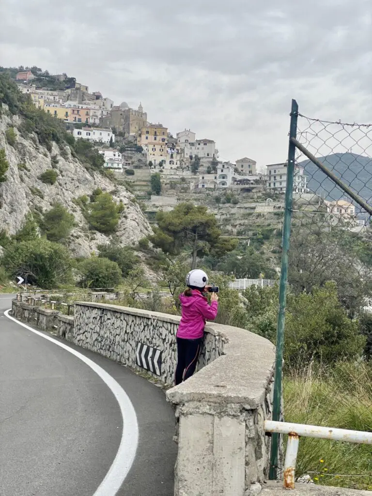 Frau mit Helm an Aussichtspunkt neben der Straße in Amalfiküste