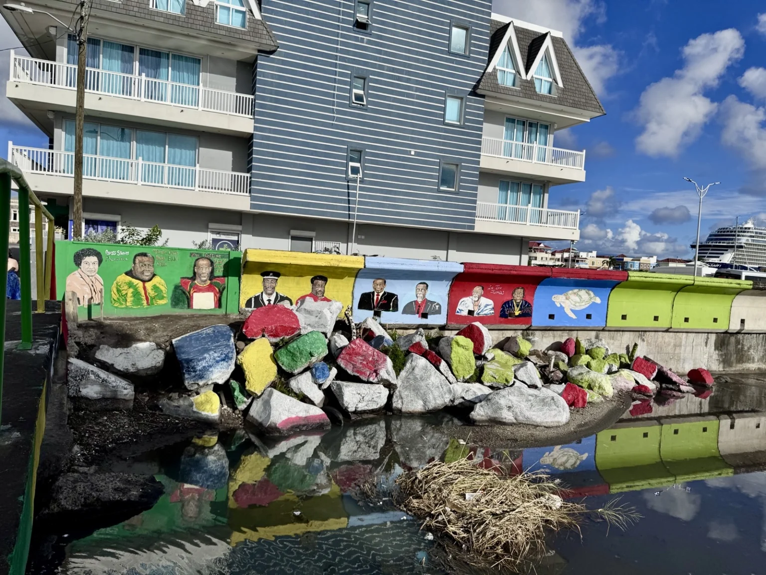 Politische Wandmalerei mit lokalen Persönlichkeiten und bunten Gedenksteinen in St. Kitts öffentlichem Park