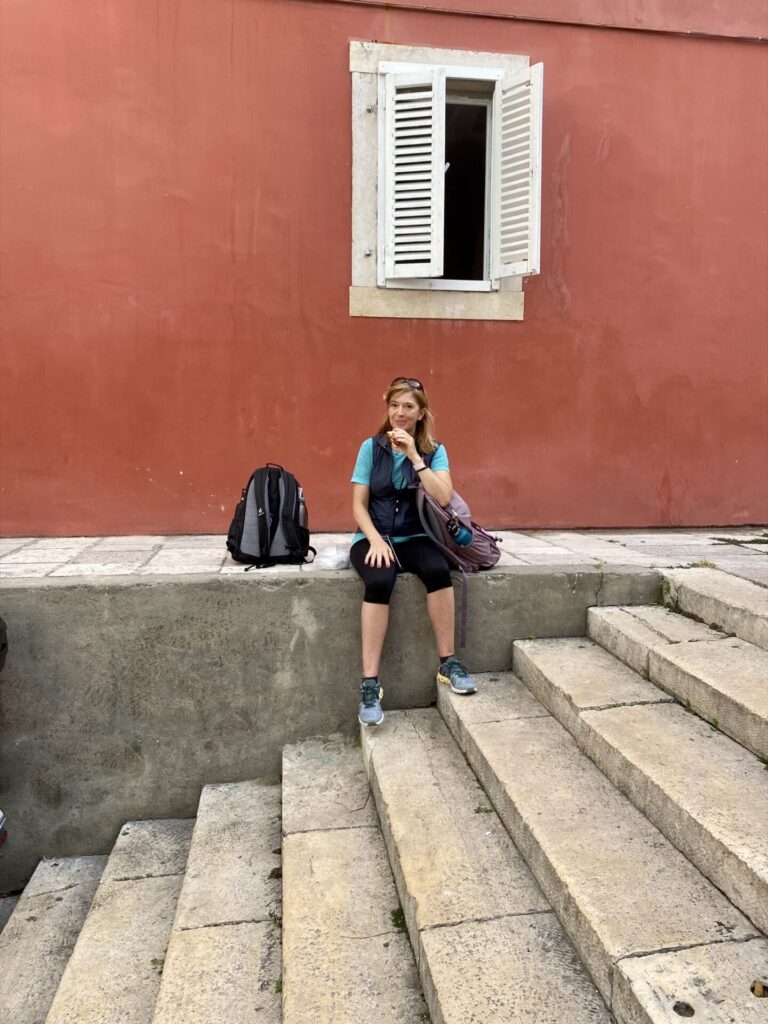 Frau sitzt auf Treppe mit weißem Fenster in Zadar